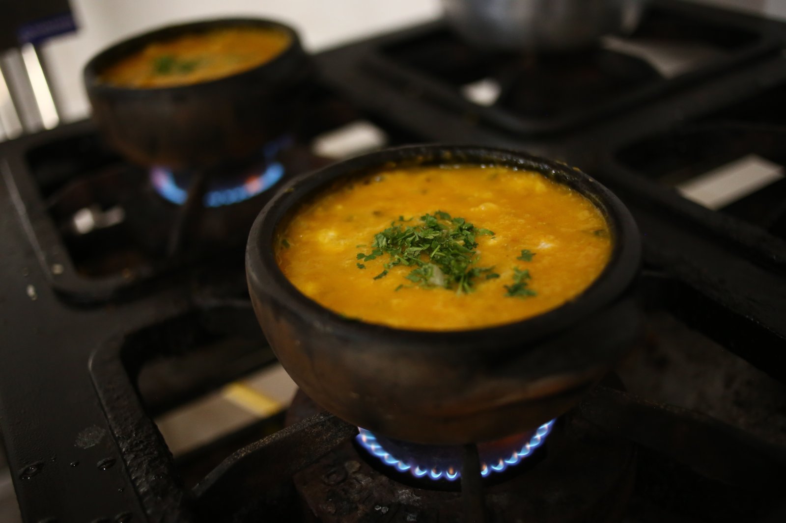Mini Moqueca de Camarão borbulhante na panela de barro com pimentões e coentro
